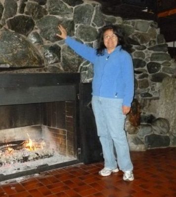 poet Muriel standing by fireplace gensturing up